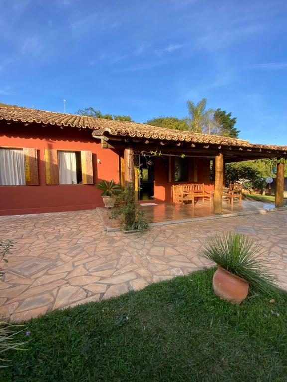 Casa vermelha com varanda, bancos de madeira e pátio de pedra